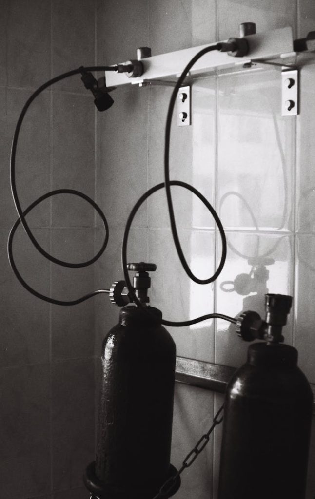 pexels-photo-12344724 Monochrome photograph showing two oxygen cylinders in a hospital setting.