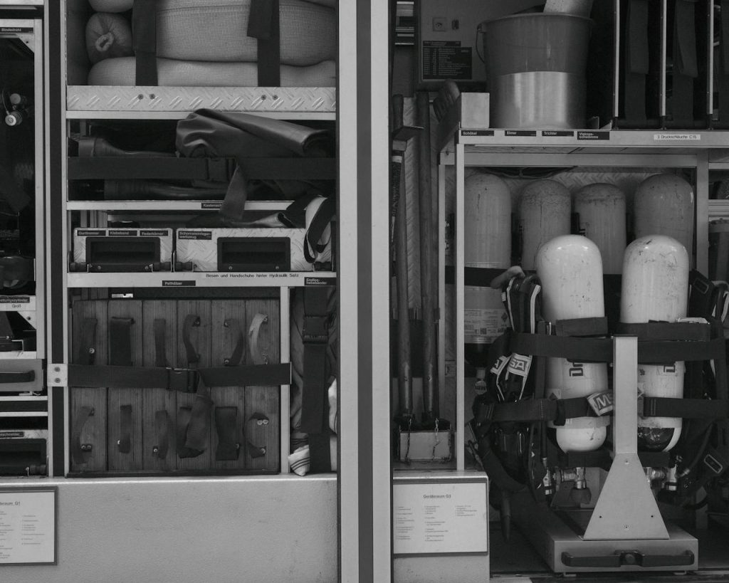 pexels-photo-27128957 Black and white photo of firetruck equipment and rescue gear neatly organized in compartments.