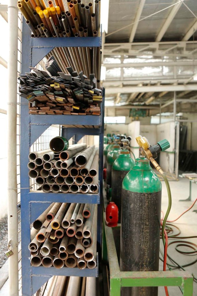 pexels-photo-9338479 Organized metal workshop with various pipes and gas tanks, perfect for industrial and construction themes.